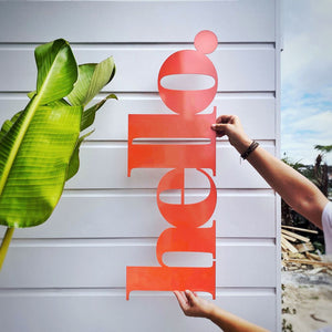 Bright orange hello wall sign welcoming guests outside the front door in New Zealand. 