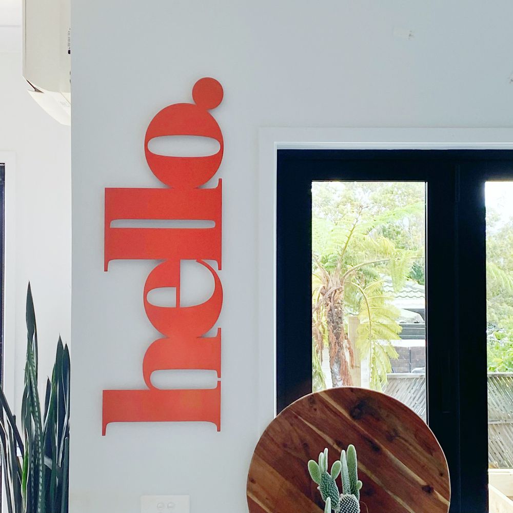 Bright orange hello wall sign welcoming guests outside the front door in New Zealand. 